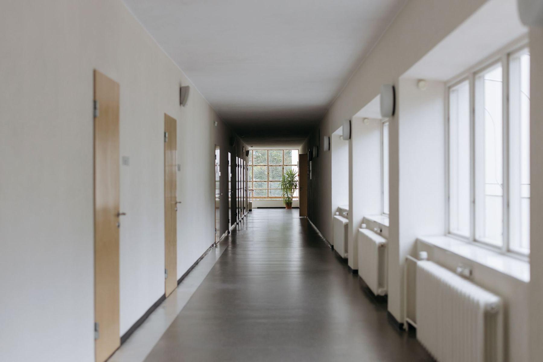 Corridor clair d'un établissement, portes et fenêtres alignées.