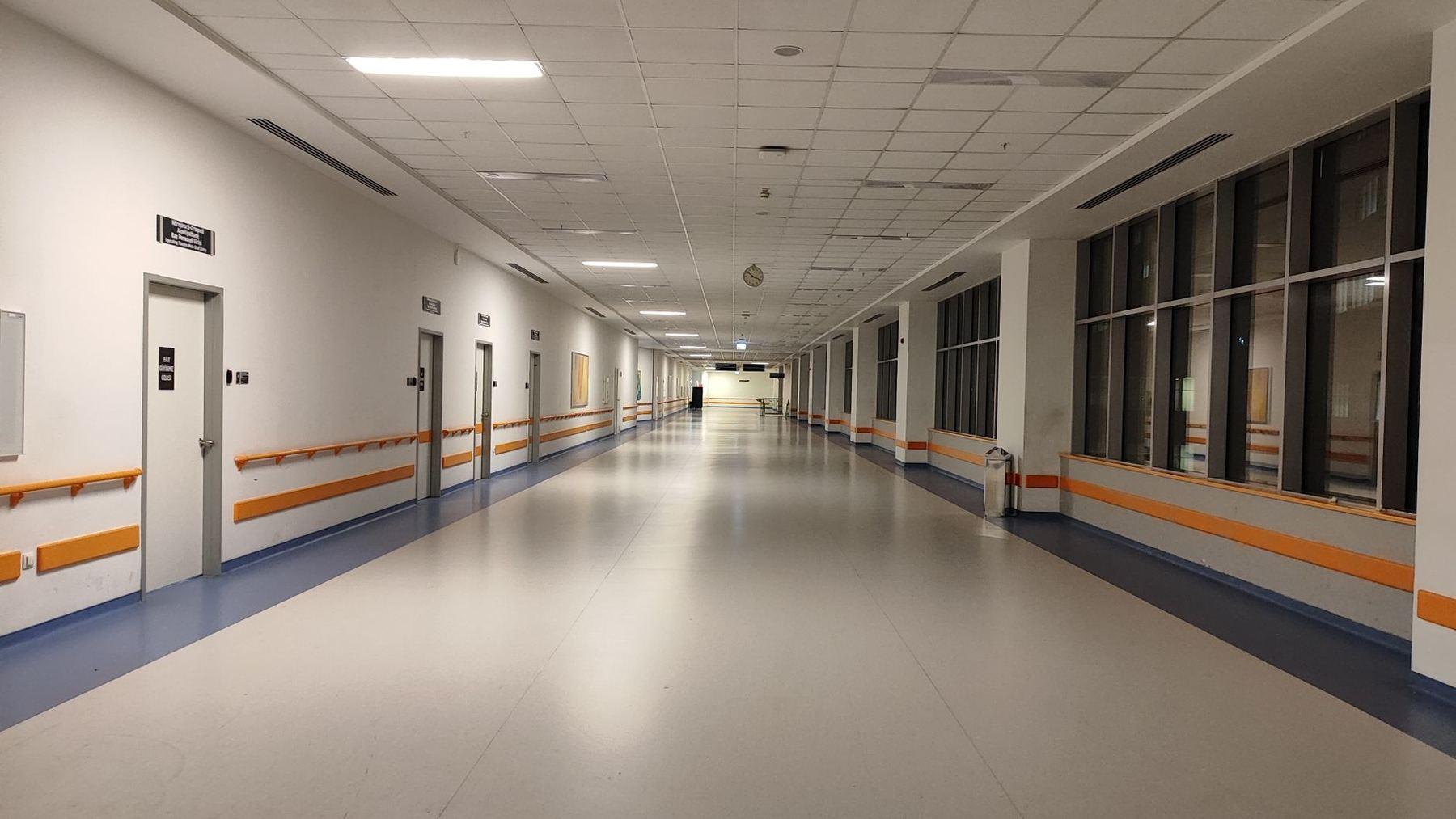 Long corridor d'un établissement de santé, mains courantes et grandes fenêtres.